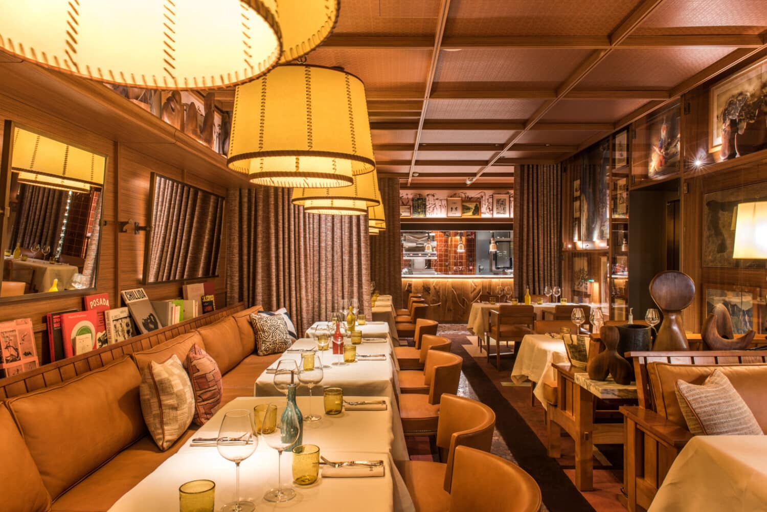 Salle du restaurant Brach Madrid avec banquettes en cuir, tables élégamment dressées et grandes suspensions lumineuses.