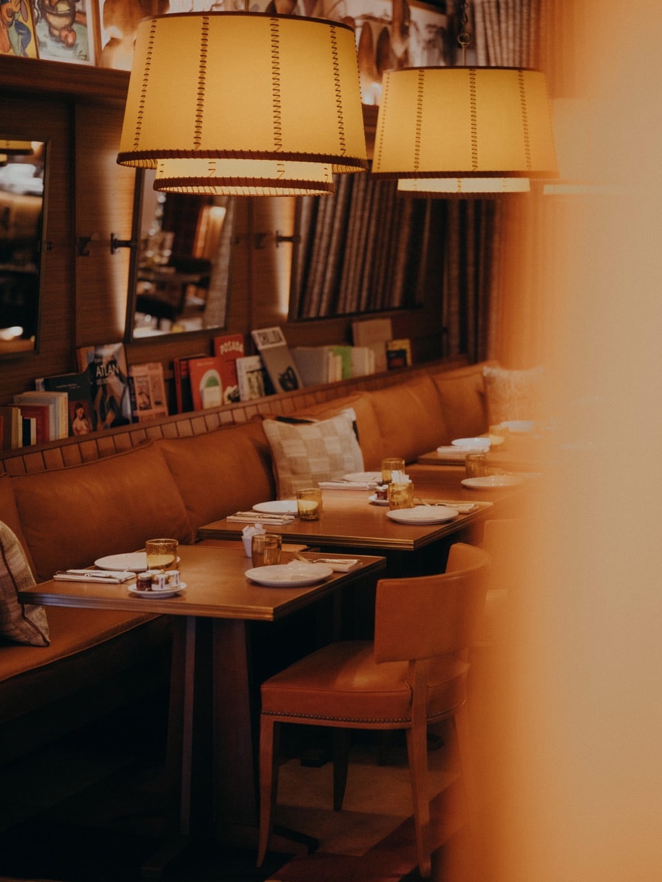 Intérieur du restaurant Brach Madrid avec banquettes en cuir, tables en bois et suspensions lumineuses.